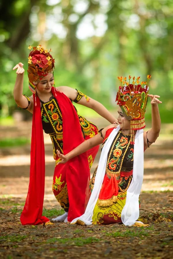 Two dancers in traditional Indonesian costume performing outdoors