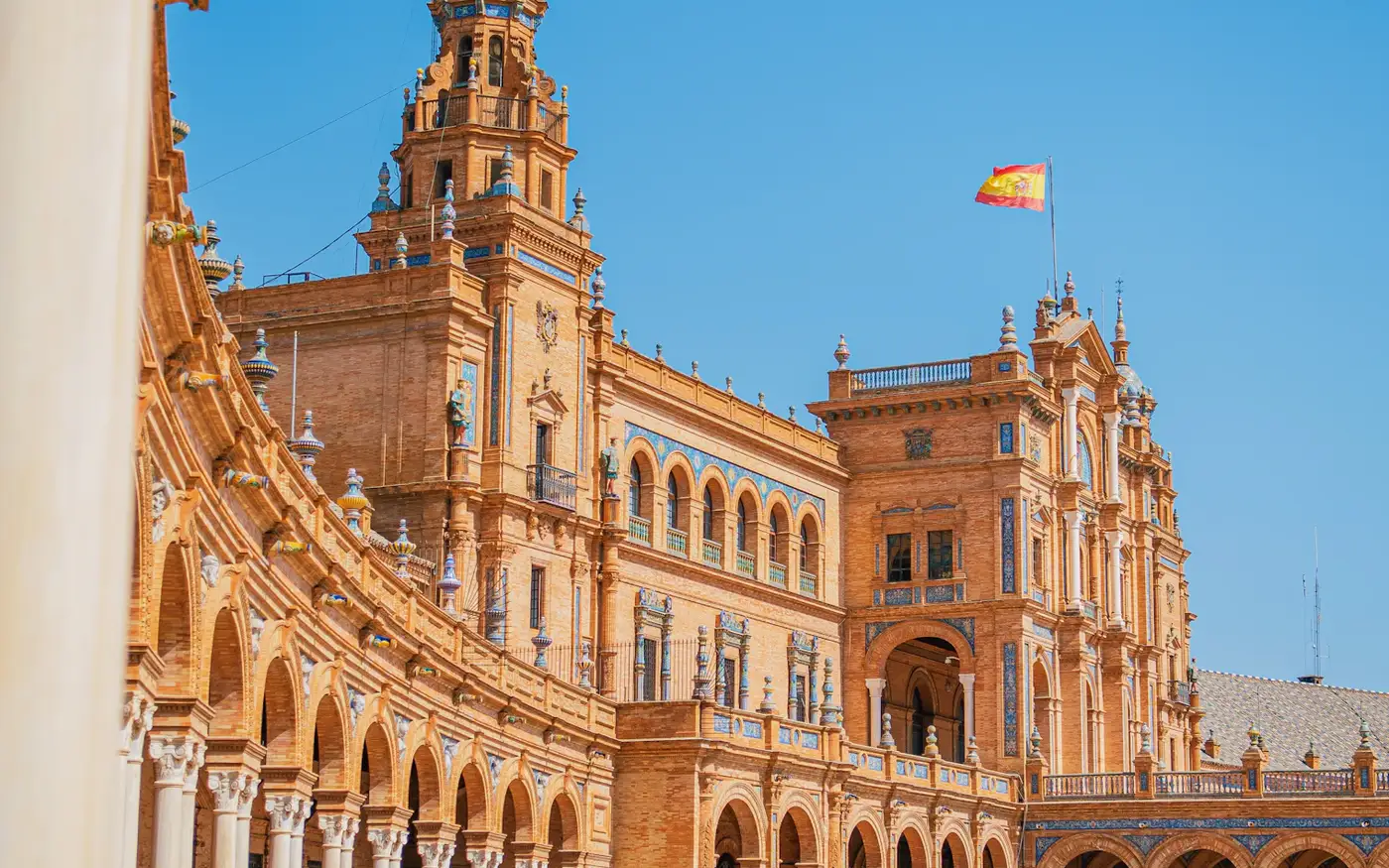 Plaza de España in Seville, Spain, with the Spanish flag flying above the brick arcade