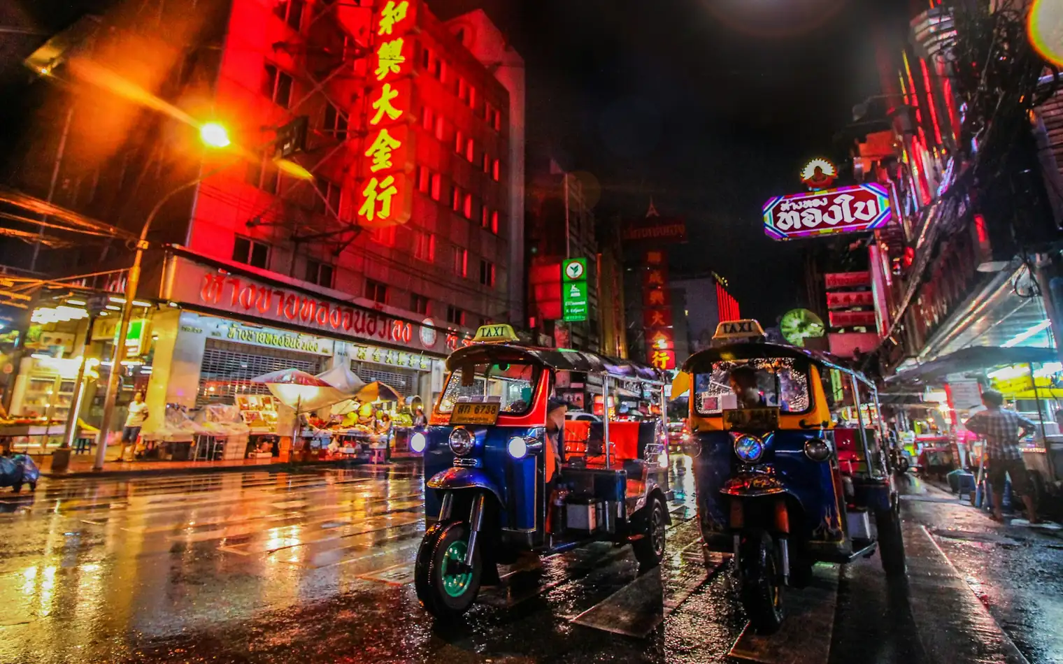 Tuk-tuks under neon signs in Bangkok's Chinatown, Thailand, at night