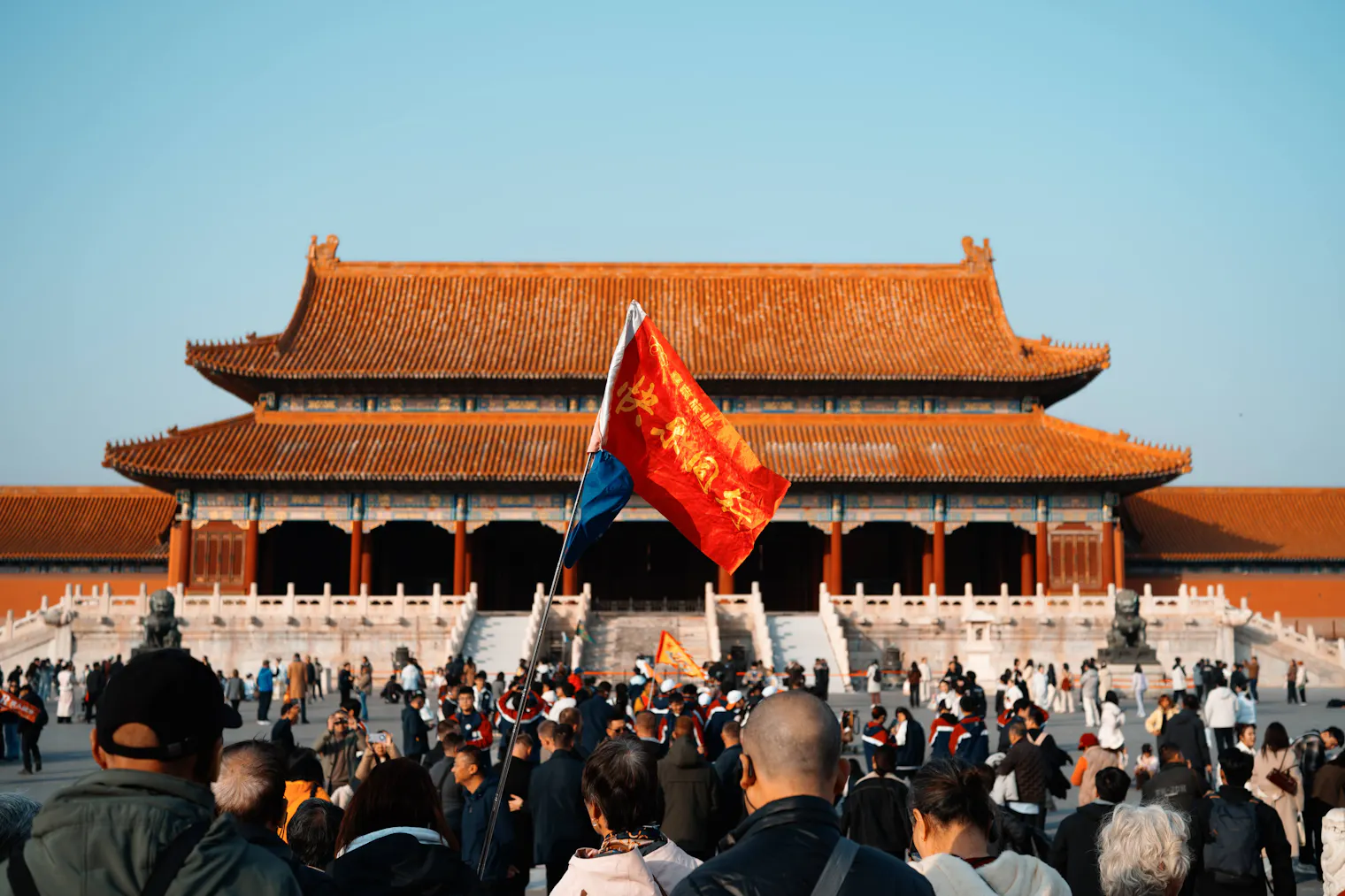 Un grupo turístico con bandera roja entre la multitud frente al Salón de la Suprema Armonía, en la Ciudad Prohibida de Pekín