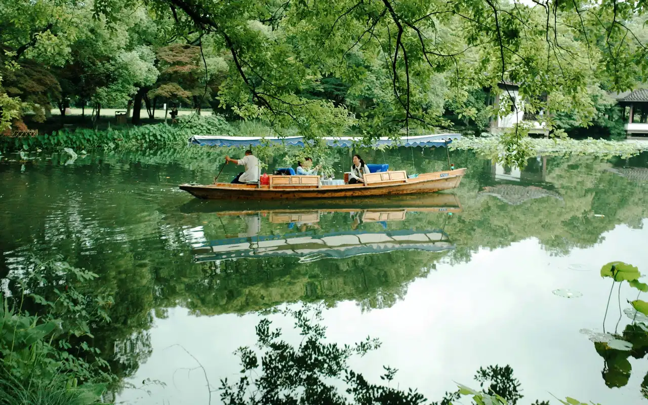 A boat on the still, tree-lined water of West Lake, Hangzhou, China