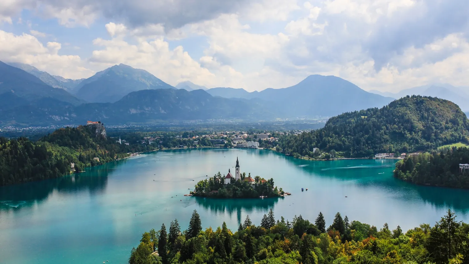 Lake Bled seen from above, with its island church, forested shores and the Julian Alps behind