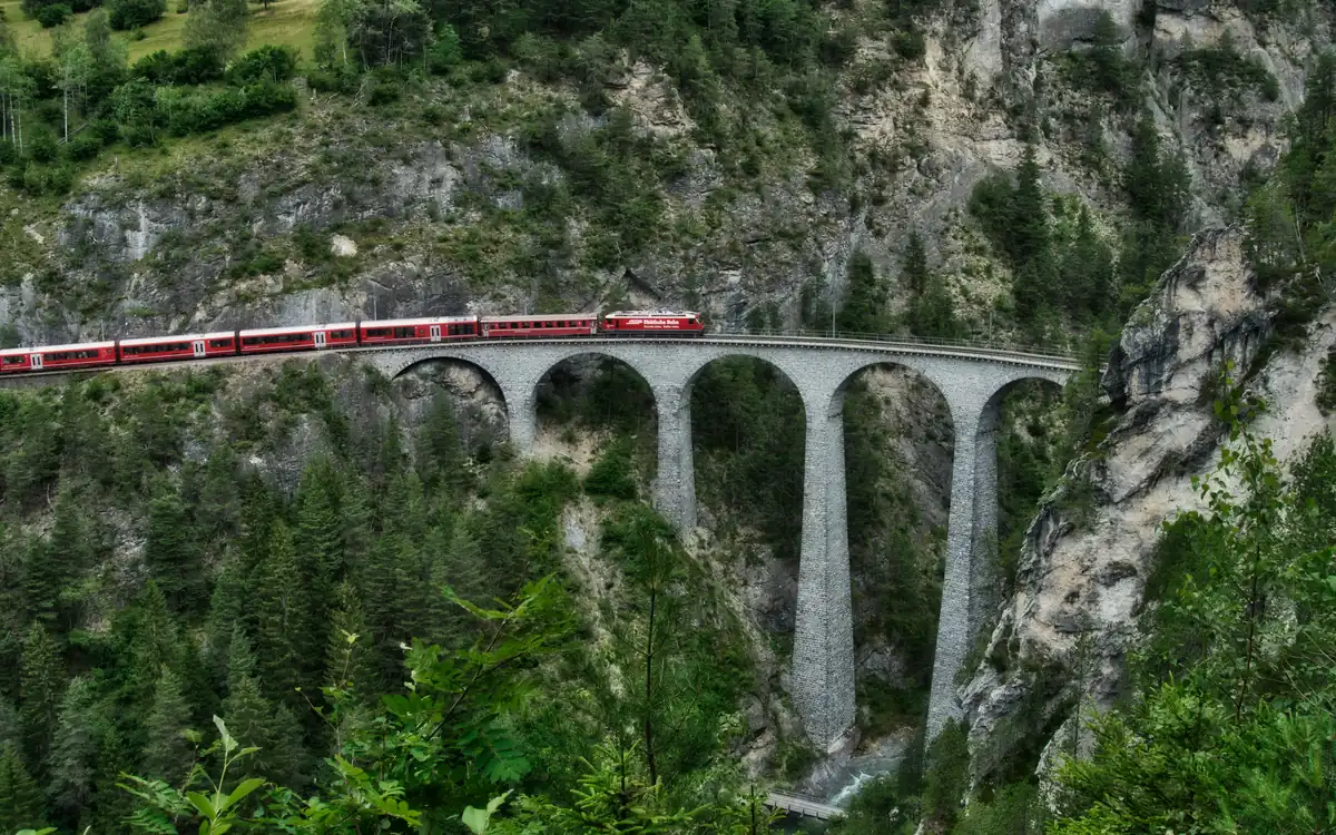 A red Rhaetian Railway train crossing the Landwasser Viaduct near Filisur, Switzerland