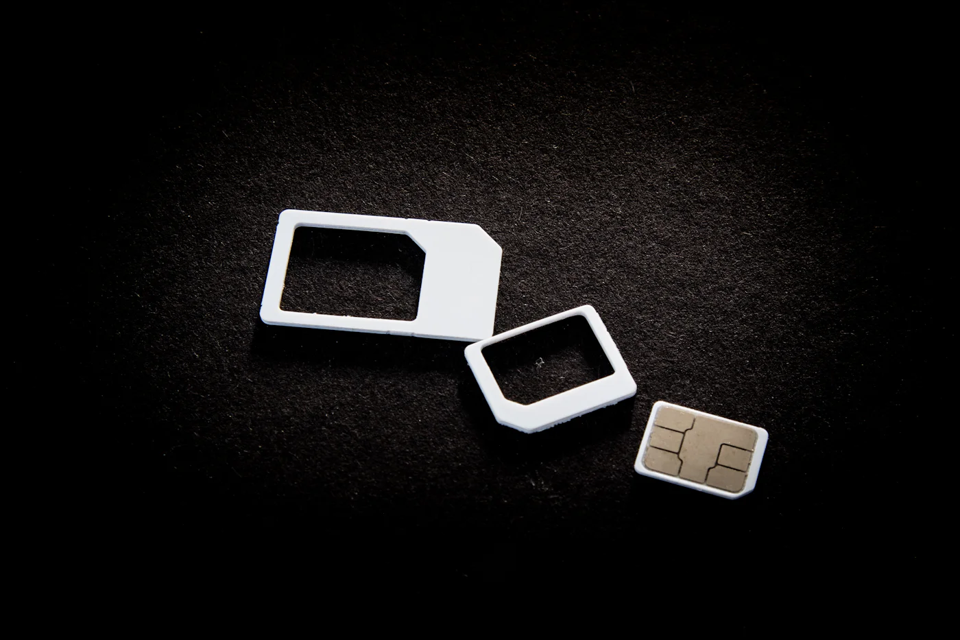 Standard, micro and nano SIM card adapters laid out on a dark surface