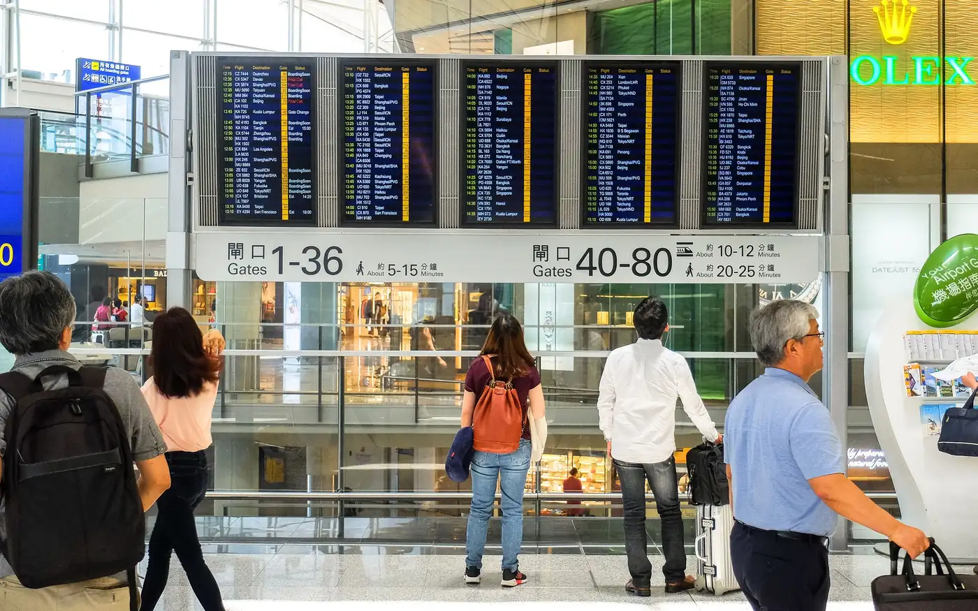 Viajeros frente a un gran panel de salidas en la terminal de un aeropuerto