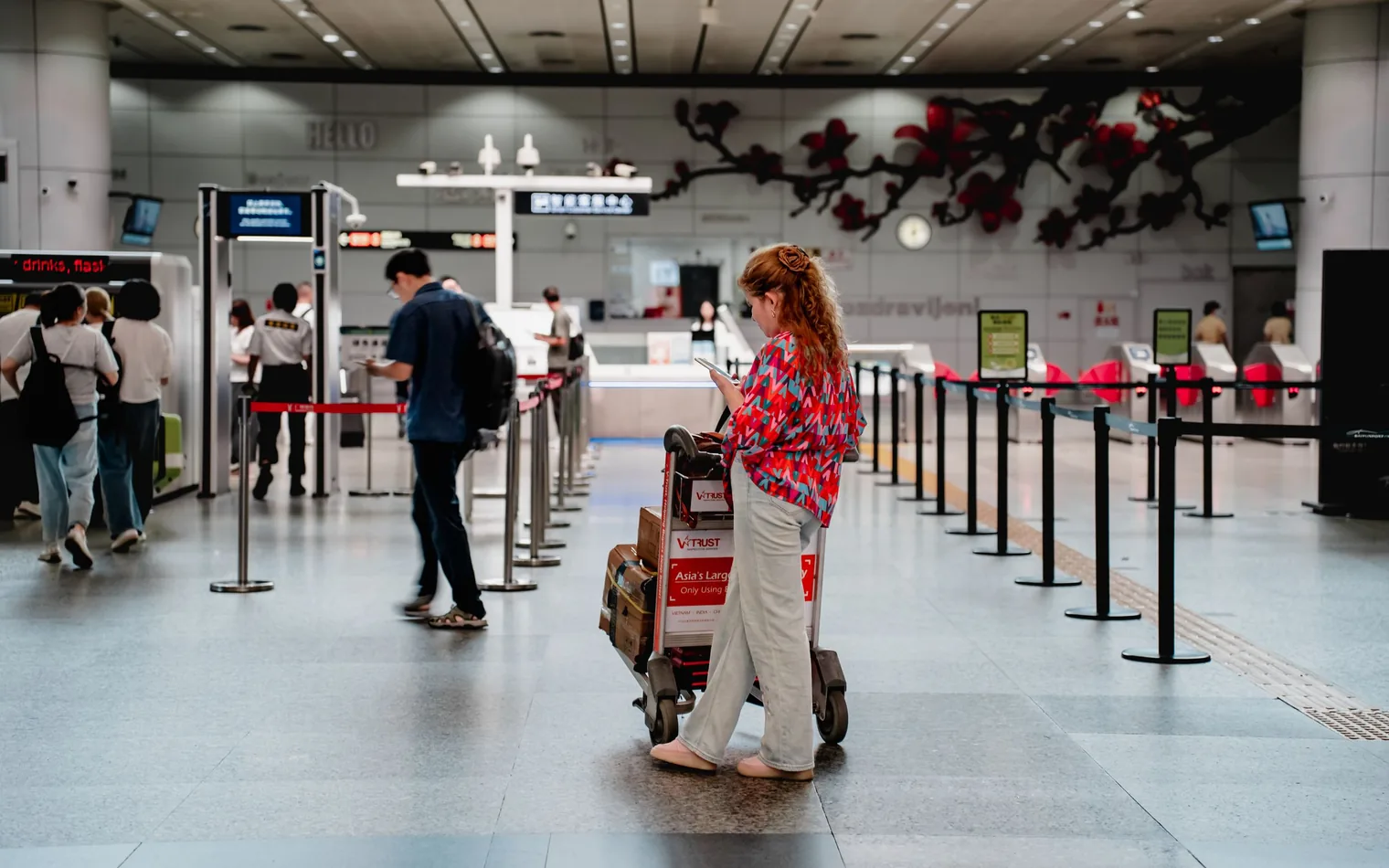 Una viajera consulta el móvil mientras espera con el equipaje en la terminal de un aeropuerto