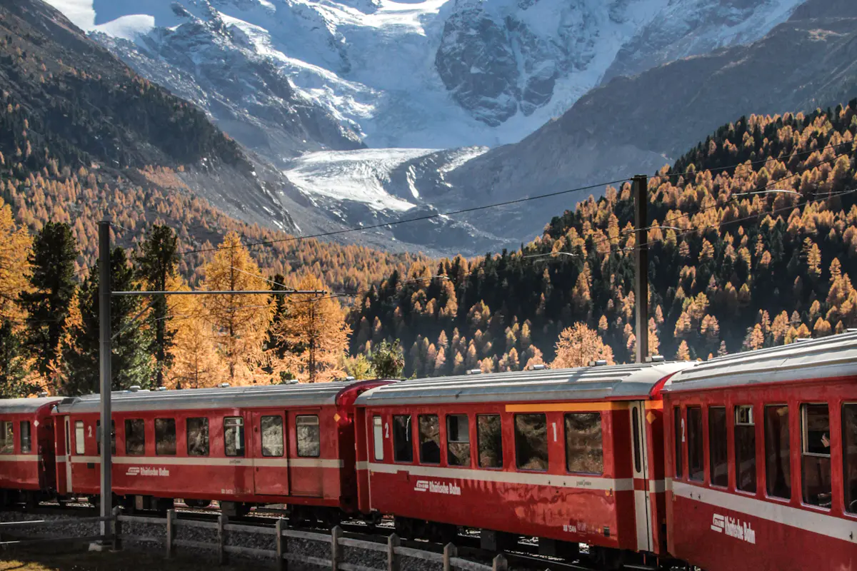 A red Bernina line train below a glacier in Graubünden, Switzerland