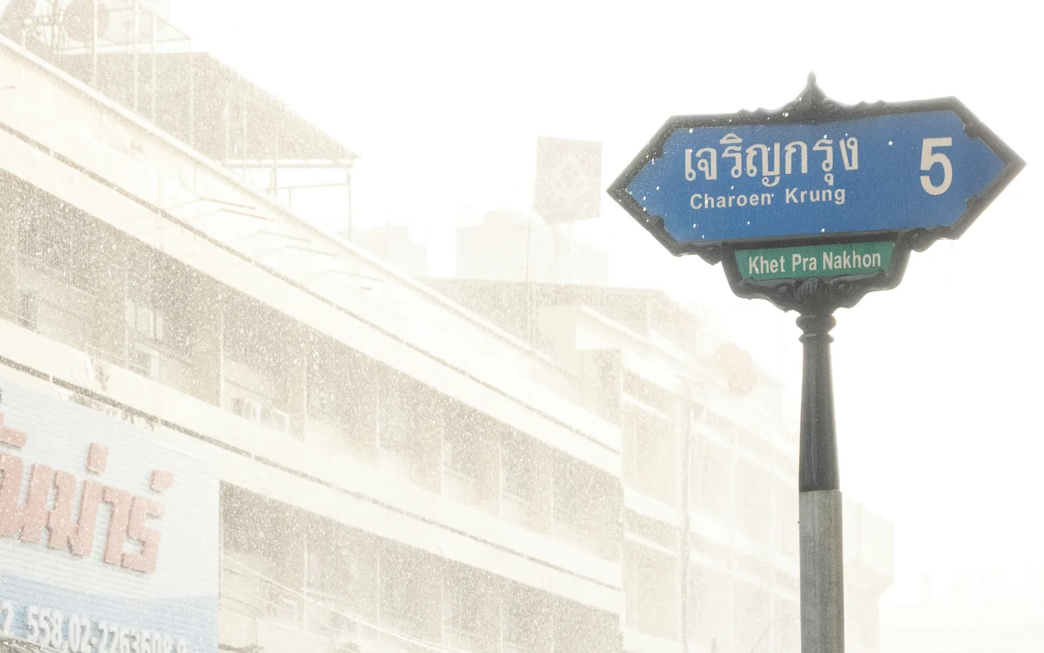 A tuk-tuk driving through heavy rain on a Bangkok street during the rainy season, Thailand
