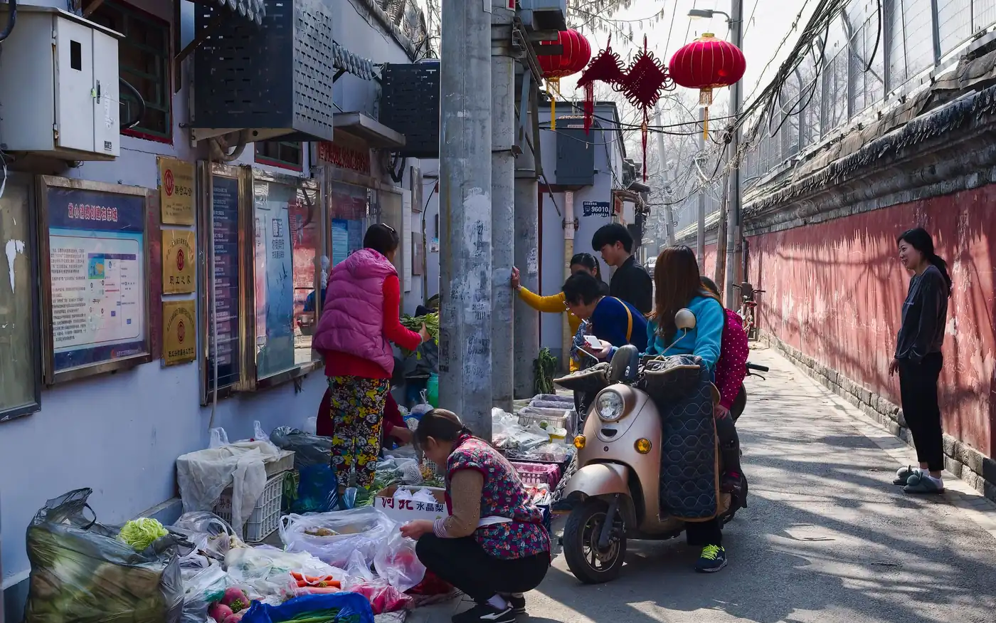 Mercado callejero en un hutong de Pekín, China, con farolillos rojos y puestos de verdura