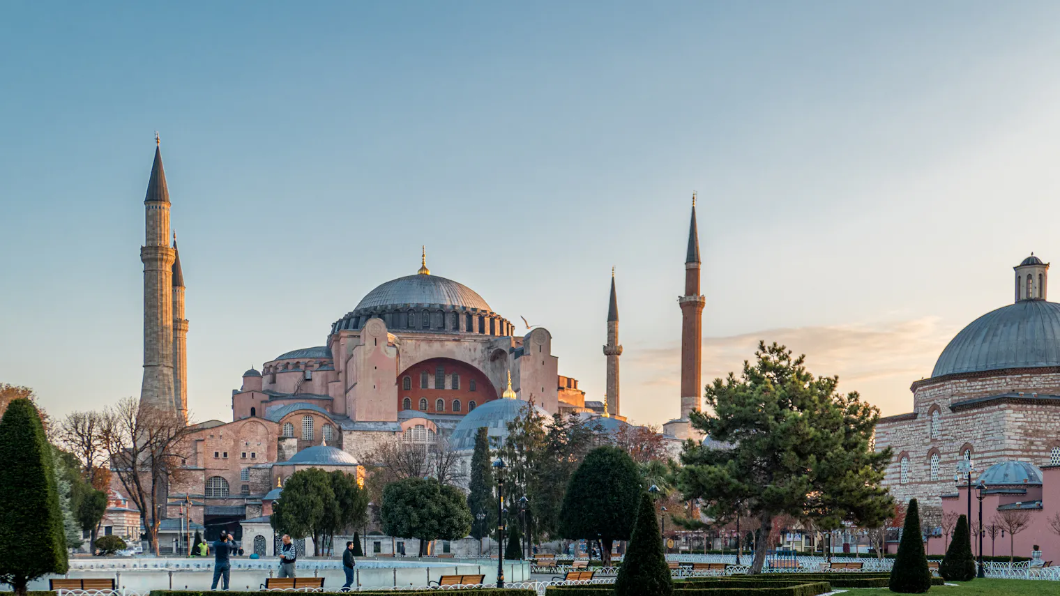 The Hagia Sophia at golden hour in Sultanahmet, Istanbul, its dome and four minarets rising above the park